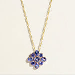Gold necklace with a flower-shaped pendant featuring purple blue tanzanite gemstones
