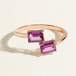 Rose gold toi et moi ring with two pink rhodolite gemstones on a light beige background