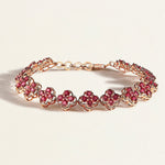 Rose gold bracelet with pink rhodolites gemstones on a light beige background