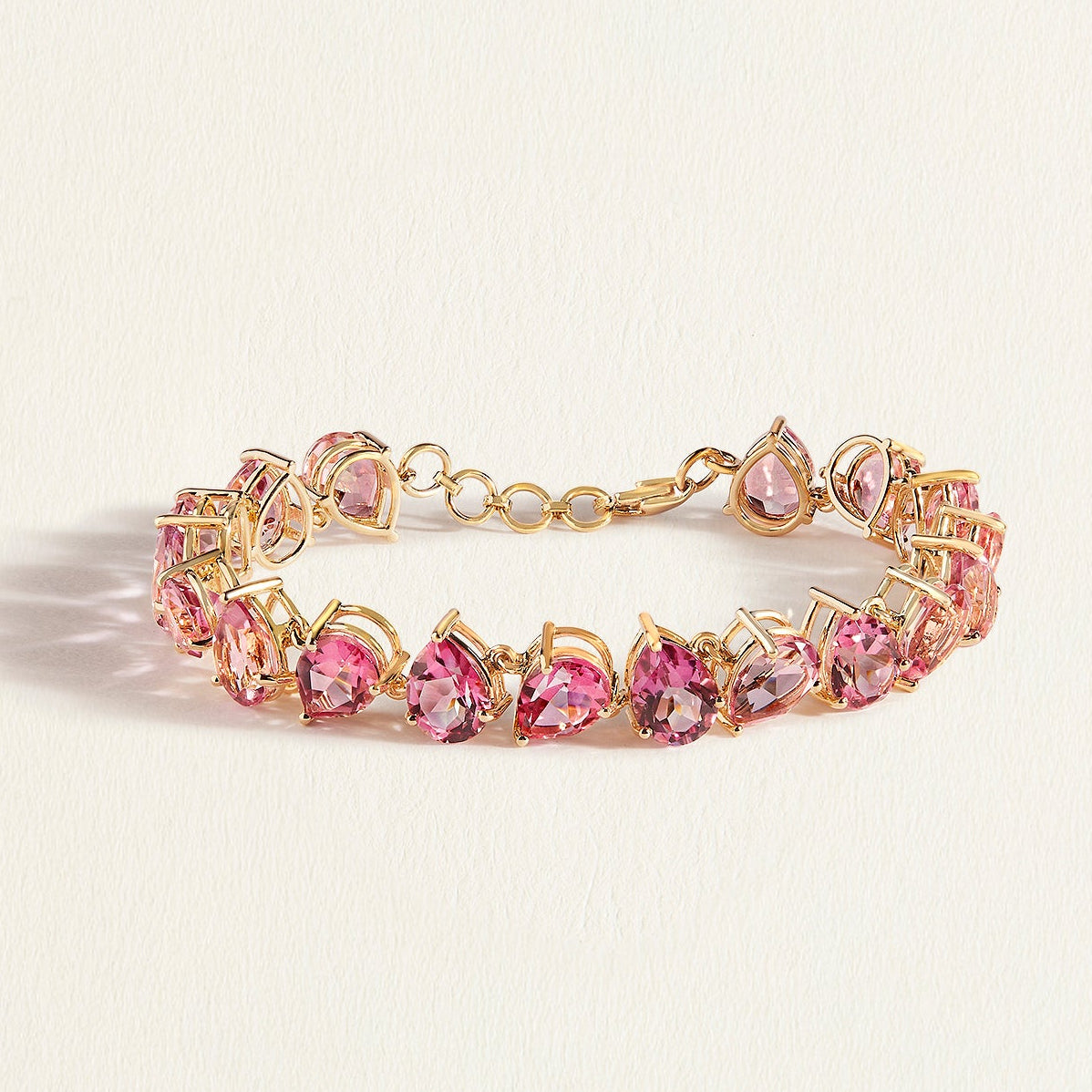 Gold bracelet with pink topaz gemstones on a light beige background