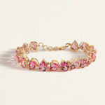 Gold bracelet with pink topaz gemstones on a light beige background