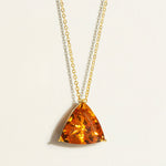 Trillion large amber brandy citrine pendant on a 14k 18k gold chain against a light background