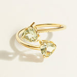 14 k Gold toi et moi ring with two green trillion amethyst gemstones on a light beige background
