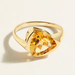 14 k Gold ring with a large trillion yellow citrine gemstone on a light beige background
