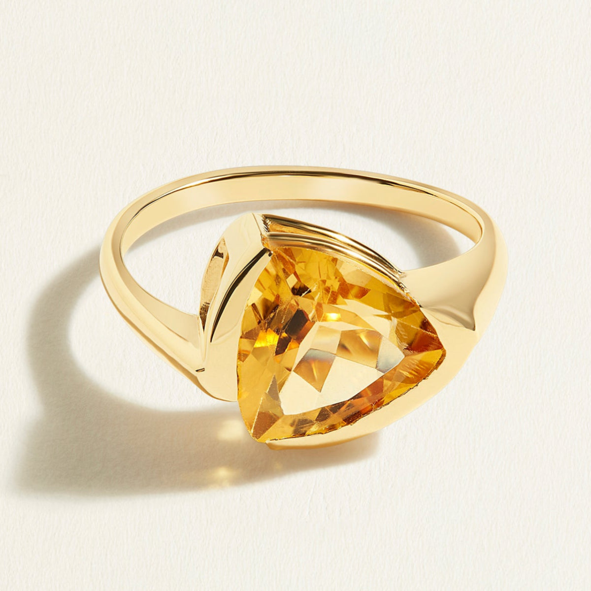 14 k Gold ring with a large trillion yellow citrine gemstone on a light beige background