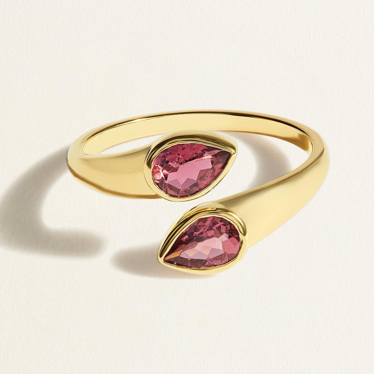 Gold toi et moi ring with two pink tourmalines gemstones on a light beige background