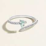 White gold diamond spiral ring with a triangular light blue aquamarine gemstone on a light beige background