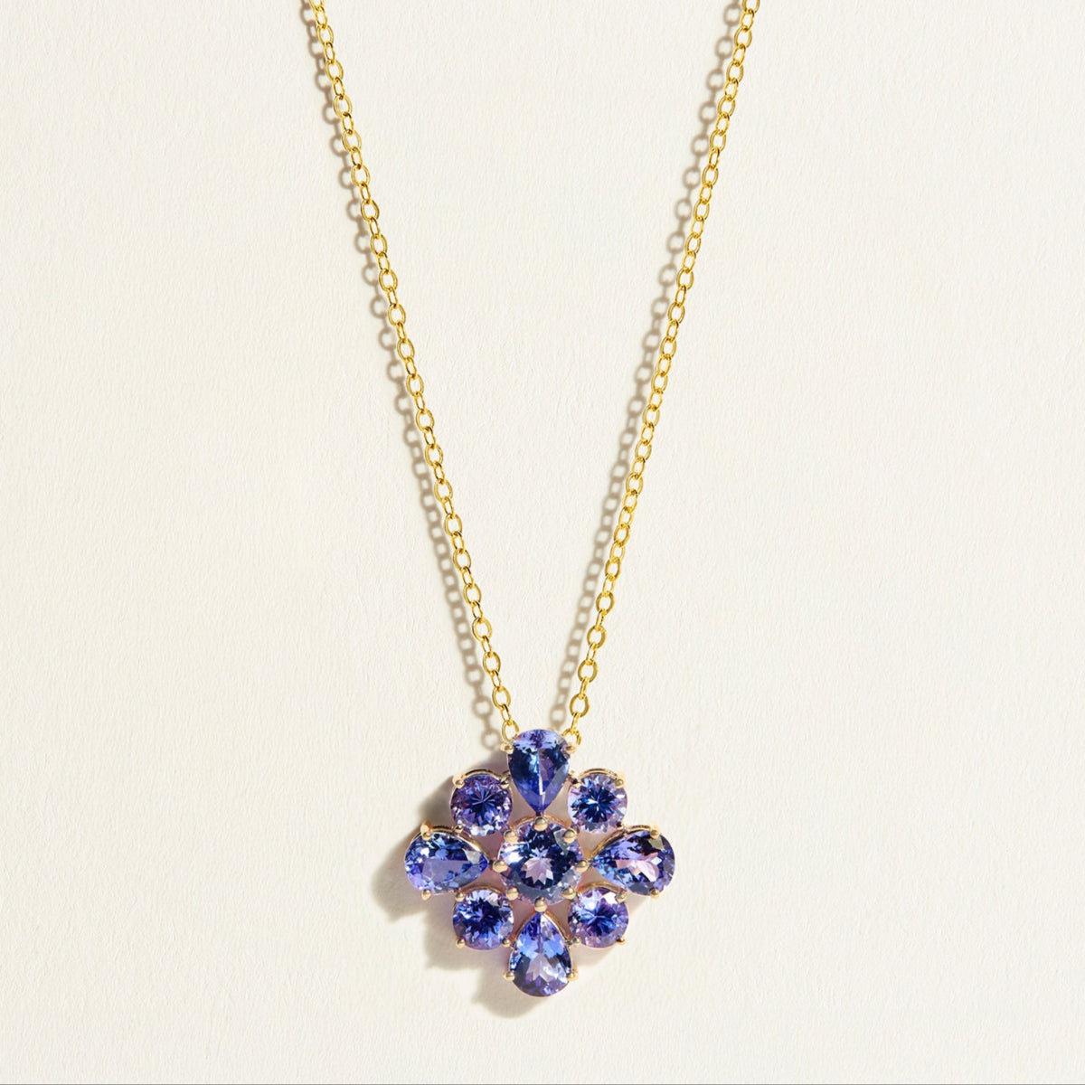 Gold necklace with a flower-shaped pendant featuring purple blue tanzanite gemstones 
