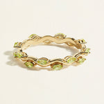 14 k gold eternity ring with a wave band with small green peridots in marquise shape