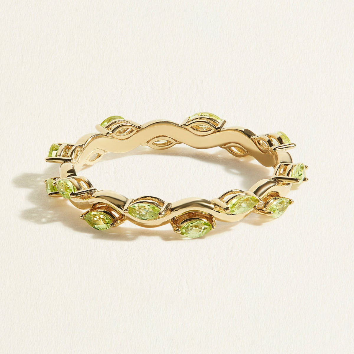 14 k gold eternity ring with a wave band with small green peridots in marquise shape