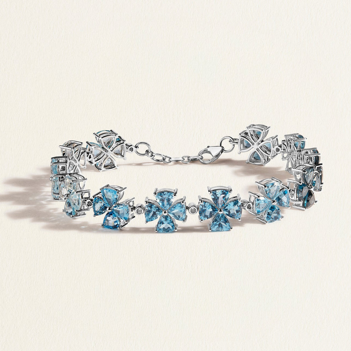 White gold  bracelet with blue gemstones on a light beige background