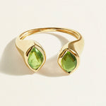 Gold signet ring with green cabochon tourmaline gemstones on a light beige background