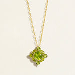 14 k 18 k Gold chain necklace with a green peridot cluster gemstone pendant on a light beige background
