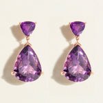 Pair of large, statement dark amethyst purple teardrop earrings in 14k rose gold on a light beige background