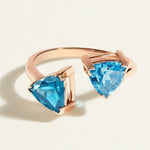 Rose gold ring toi et moi  with swiss blue and london blue topaz gemstones on a light beige background