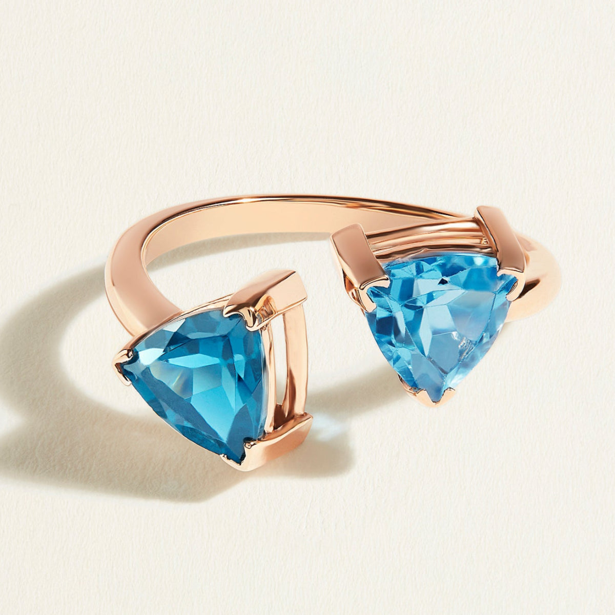 Rose gold ring toi et moi  with swiss blue and london blue topaz gemstones on a light beige background