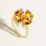 Gold ring with four large yellow  citrine gemstones  in a clover pattern on a light background