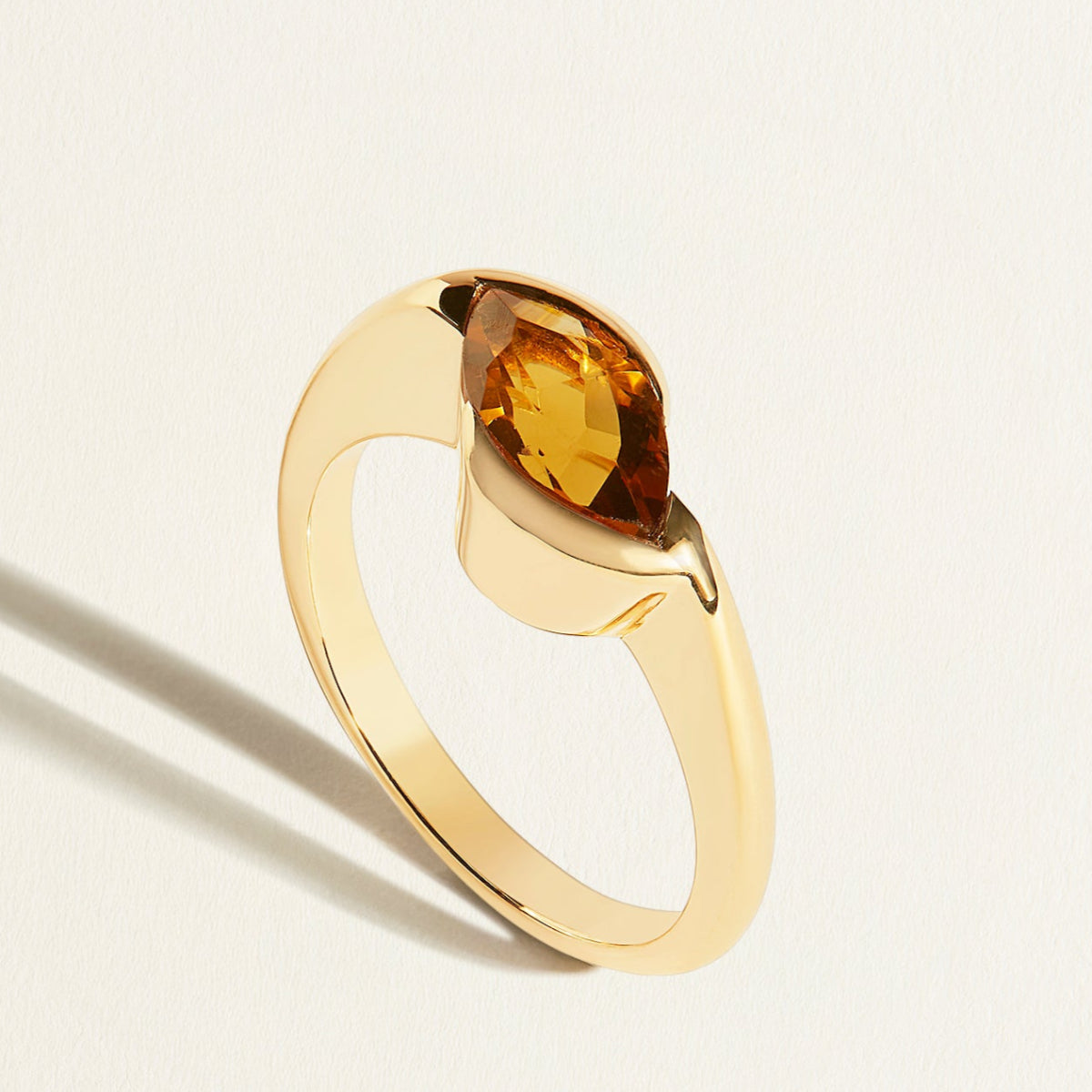 Gold ring with a brown marquise  bear quartz gemstone on a light  background