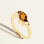 Gold ring with a brown marquise  bear quartz gemstone on a light  background