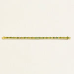 14 k Gold tennis bracelet with green oval tourmaline gemstones on a light beige background
