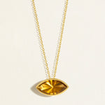 Gold chain necklace with a deep yellow east west setting olive quartz gemstone pendant on a light beige background