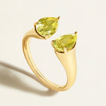 Gold open signet ring with two pear-shaped yellow lemon quartz gemstones on a light background
