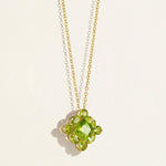 14 k Gold chain necklace with a green peridot cluster gemstone designer pendant on a light beige background