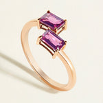 Rose gold  toi et moi ring with two pink rhodolite gemstones on a light beige background
