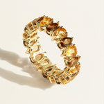 14 k Gold eternity ring with alternating brown pear smoky quartz and  pear yellow citrine gemstones on a light beige background