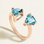 Rose gold ring toi et moi  with swiss blue and london blue topaz gemstones on a light beige background