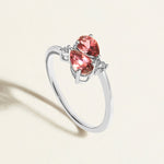 White gold toi et moi ring with red pink tourmalines gemstones  and diamond accents on a light beige background
