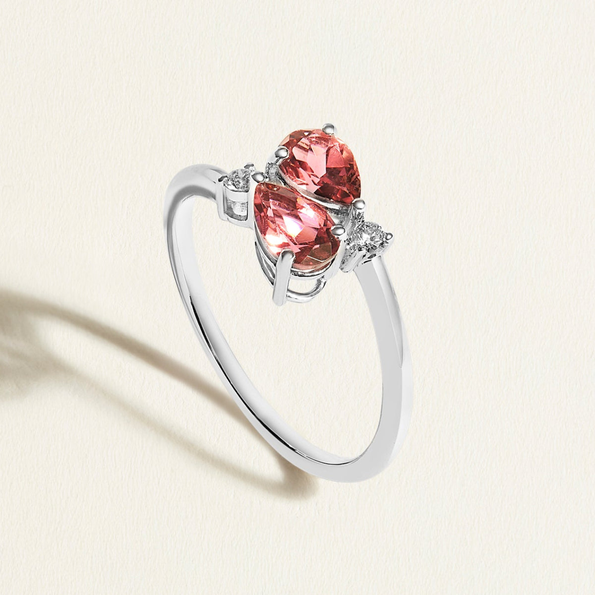 White gold toi et moi ring with red pink tourmalines gemstones  and diamond accents on a light beige background