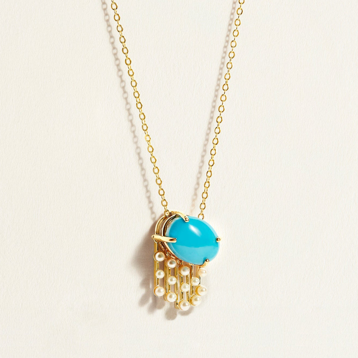 Necklace chain with a turquoise pendant and pearl chain on a light background