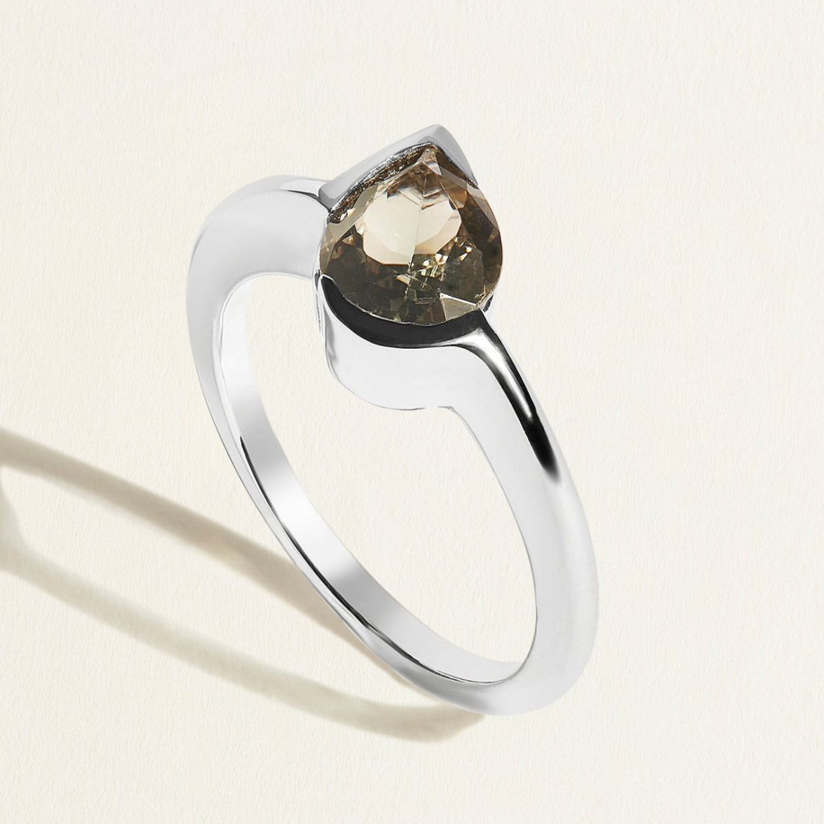 white gold ring with a gray green tourmaline pear gemstone on a light background