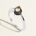 white gold ring with a gray green tourmaline pear gemstone on a light background