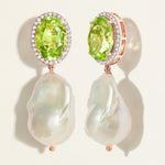 Pair of earrings with oval green peridot gemstones with diamond halo  and  baroque pearl drops on a light background