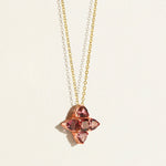 Gold Necklace with a rose gold pendant featuring pink tourmalines gemstones in a clover shape on a light background