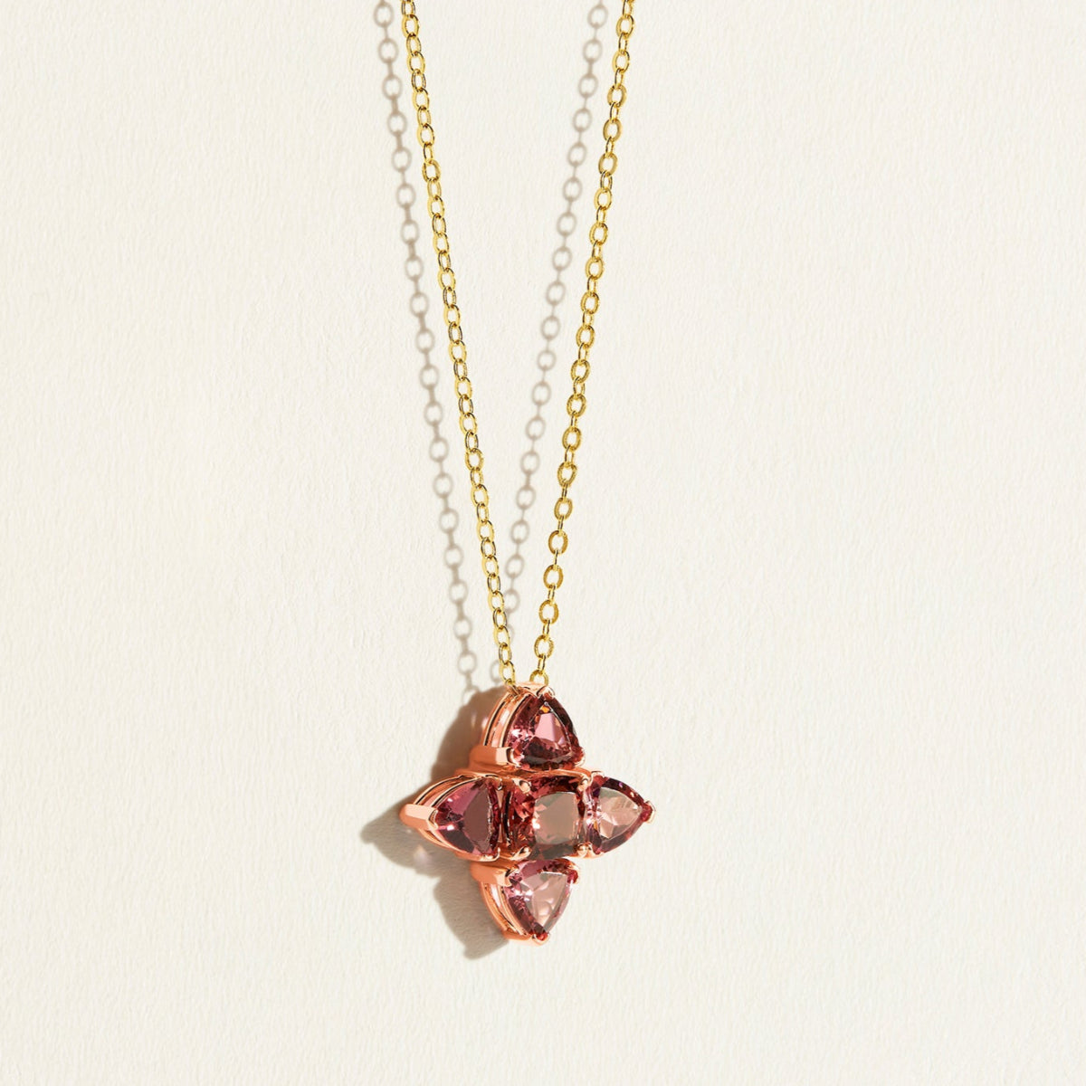 Gold Necklace with a rose gold pendant featuring pink tourmalines gemstones in a clover shape on a light background