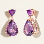 Red carpet festivePurple teardrop dark amethyst  cocktail earrings with 18 k rose gold settings on a light beige background
