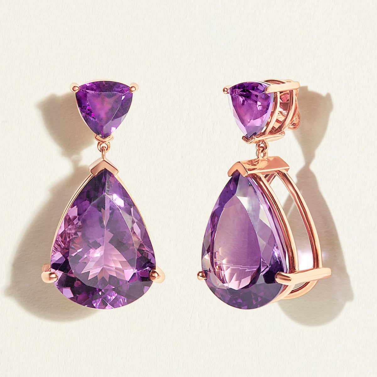 Red carpet festivePurple teardrop dark amethyst  cocktail earrings with 18 k rose gold settings on a light beige background