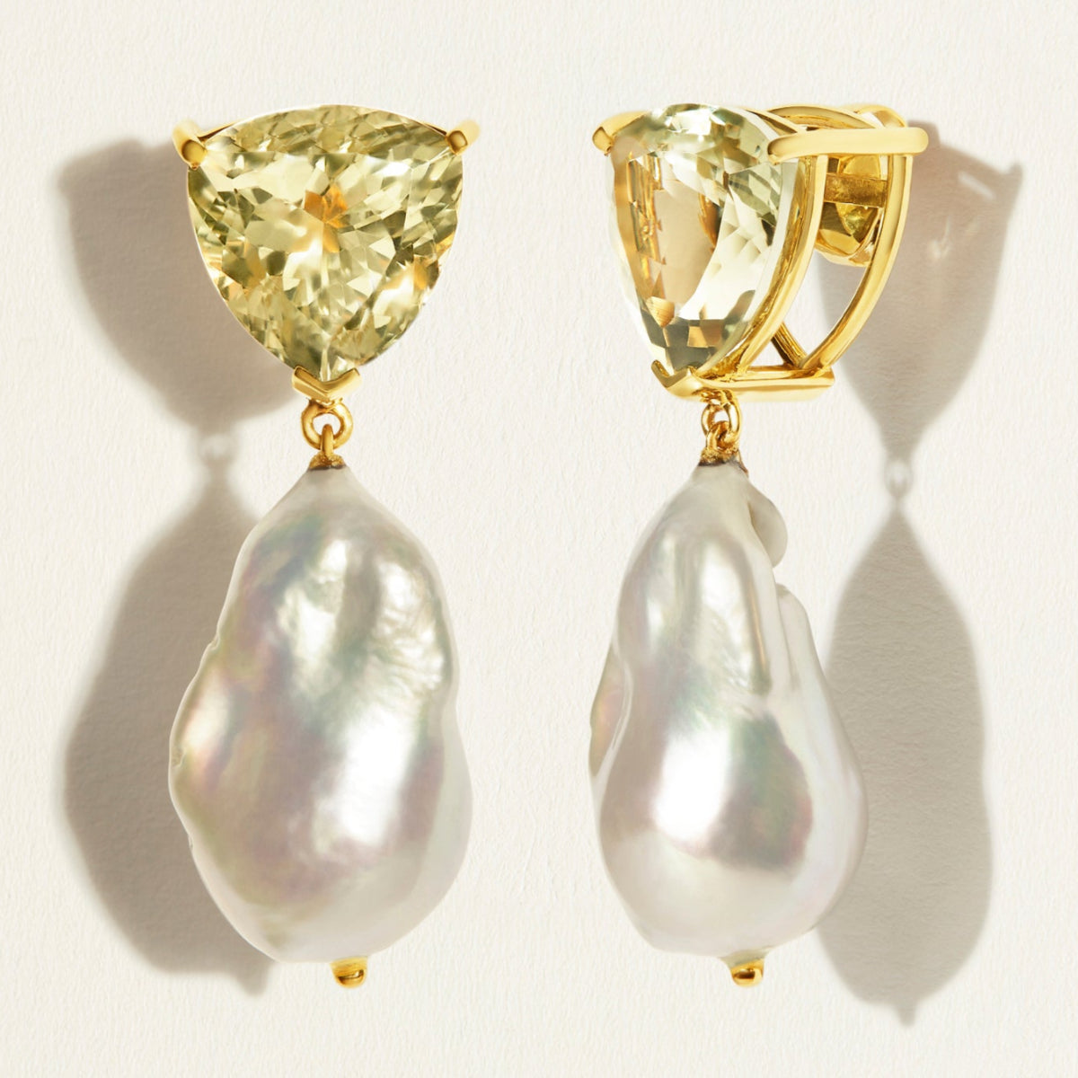 Large , designer , modern Gold earrings with green amethyst and baroque pearls on a light background