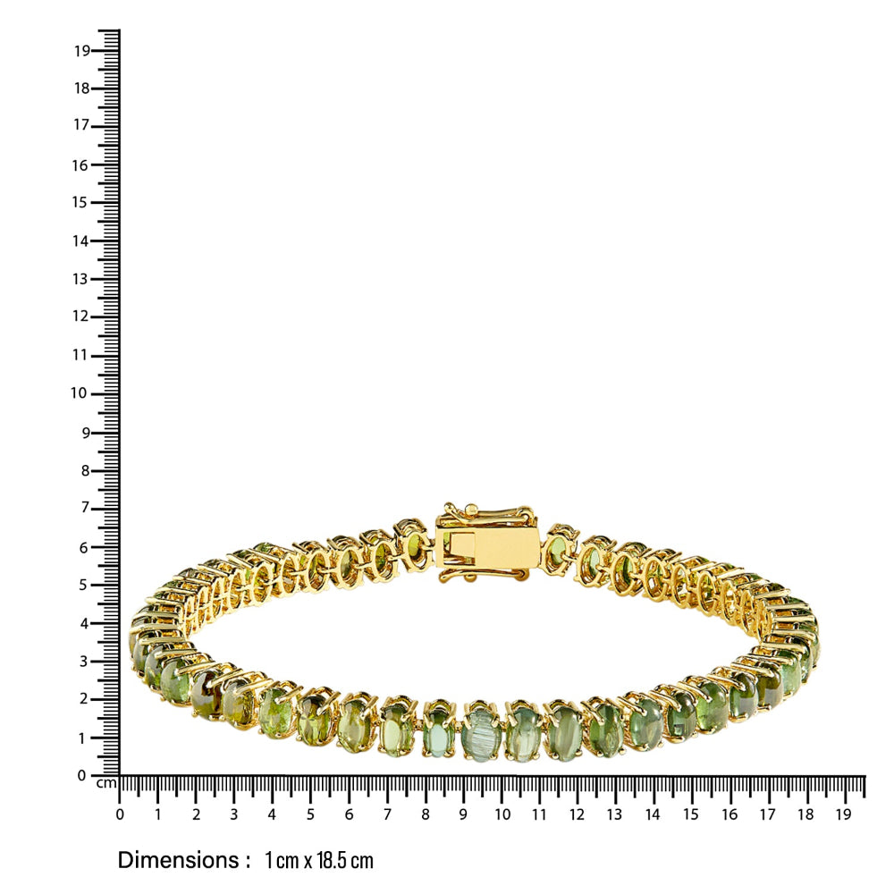 Gold bracelet with green gemstones next to a ruler for size reference on a white background