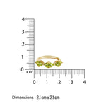 Gold birthstone ring with green peridot gemstones next to a ruler on a white background