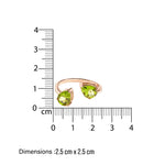 Rose gold ring with green gemstones next to a ruler showing dimensions