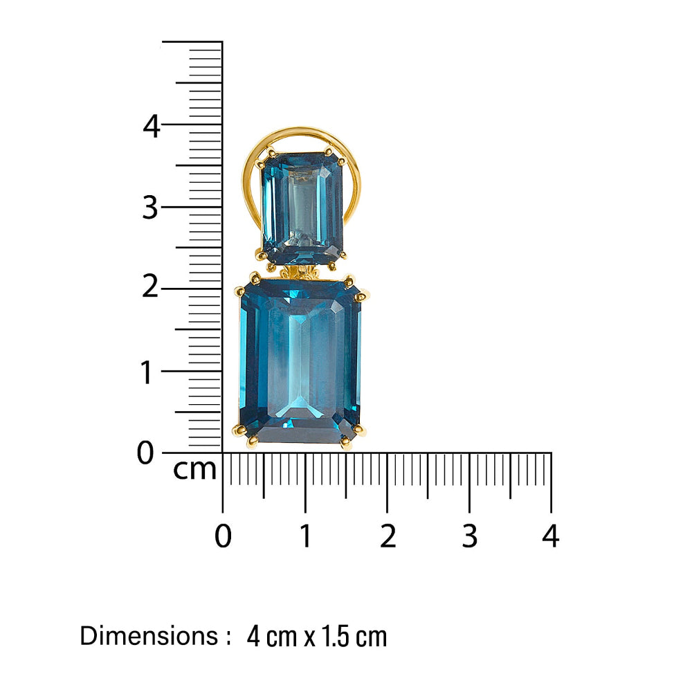 Gold cocktail designer earring with blue topaz gemstones being measured against a ruler on a white background