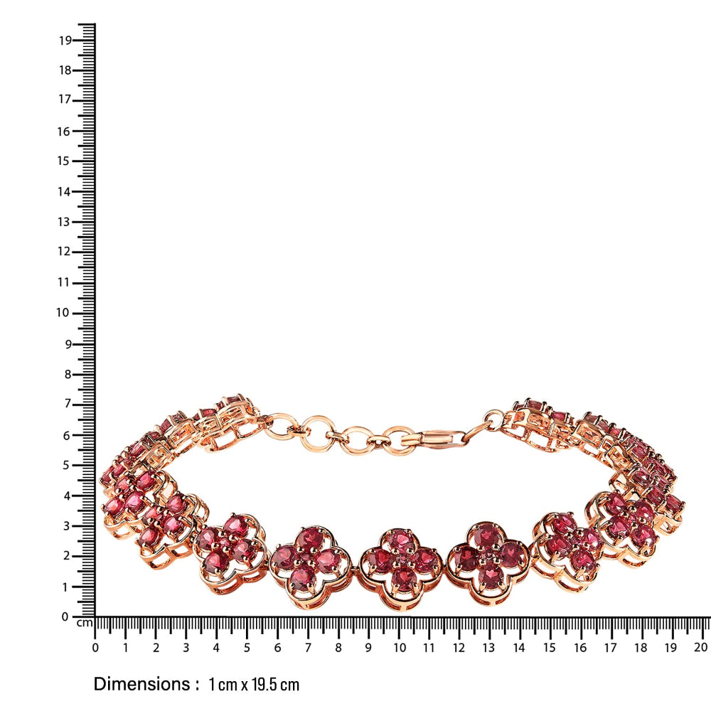 Rose gold bracelet with red gemstones next to a ruler on a white background