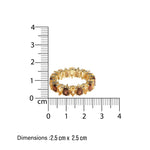 Gold eternity ring with pear shaped brown and yellow smoky quartz and citrines stones next to a ruler showing its dimensions on a white background