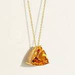 solid Gold chain statement necklace with a orange yellow citrine gemstone pendant on a light beige background