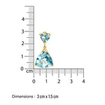 Gold cocktail earring with blue gemstones next to a ruler showing dimensions