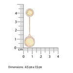 Gold hanging chain earrings with opal gemstones next to a ruler for size reference on a white background